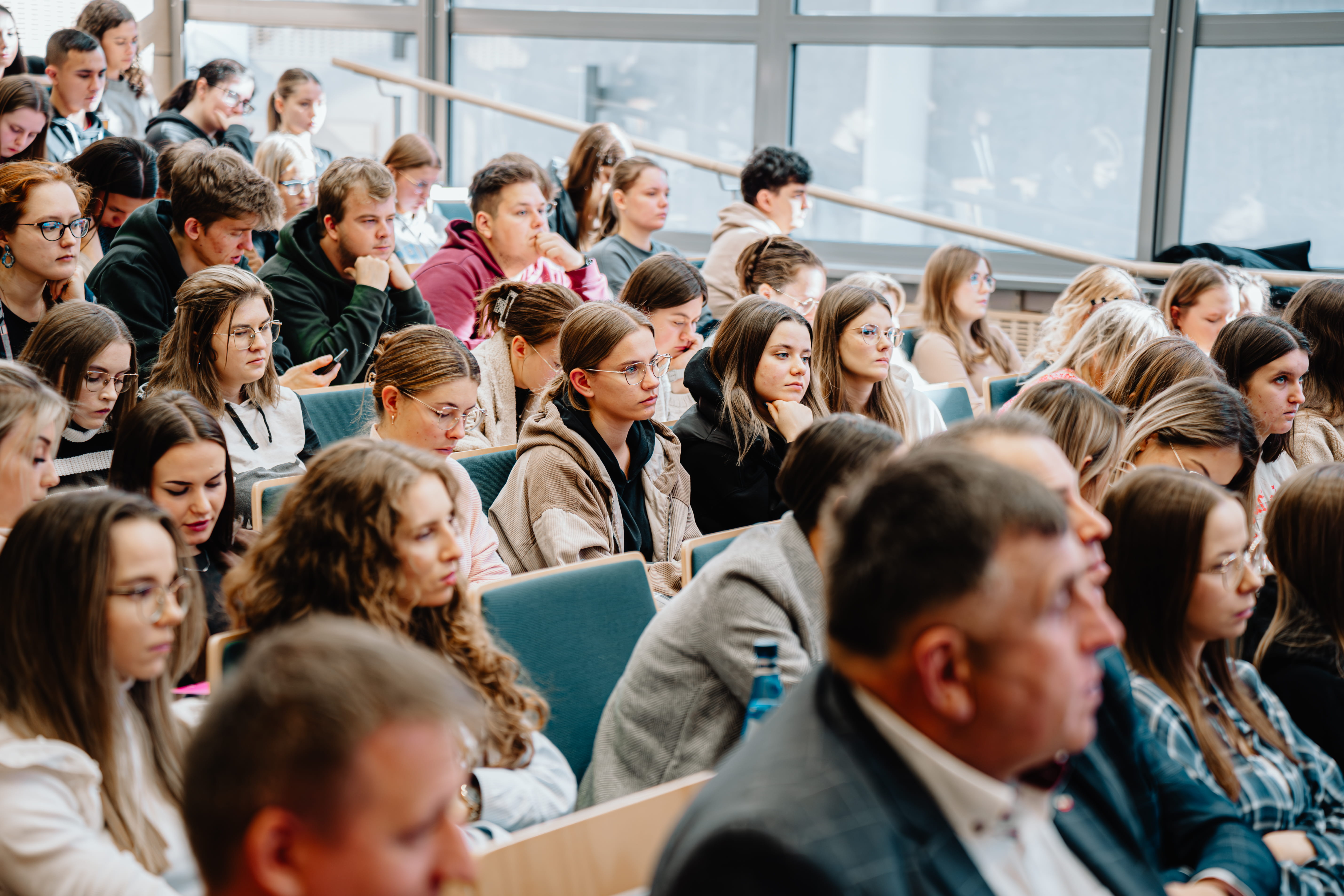 Osoby siedzą w auli i uczestniczą w wykładzie.