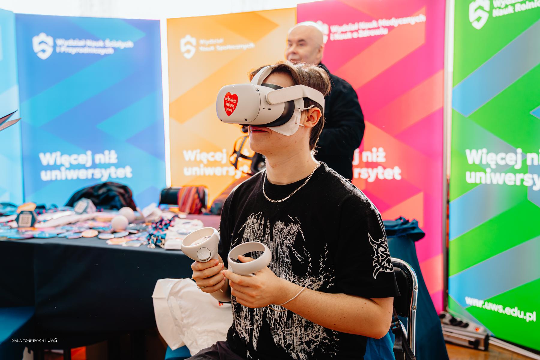 Uczeń w googlach VR uczestniczy w promocji na targach.