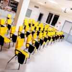 Sala symulacji medycznej - Jasna sala Uniwersytetu w Siedlcach z rzędami nowoczesnych żółtych krzeseł z pulpitami.