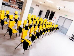 Sala symulacji medycznej - Jasna sala Uniwersytetu w Siedlcach z rzędami nowoczesnych żółtych krzeseł z pulpitami.